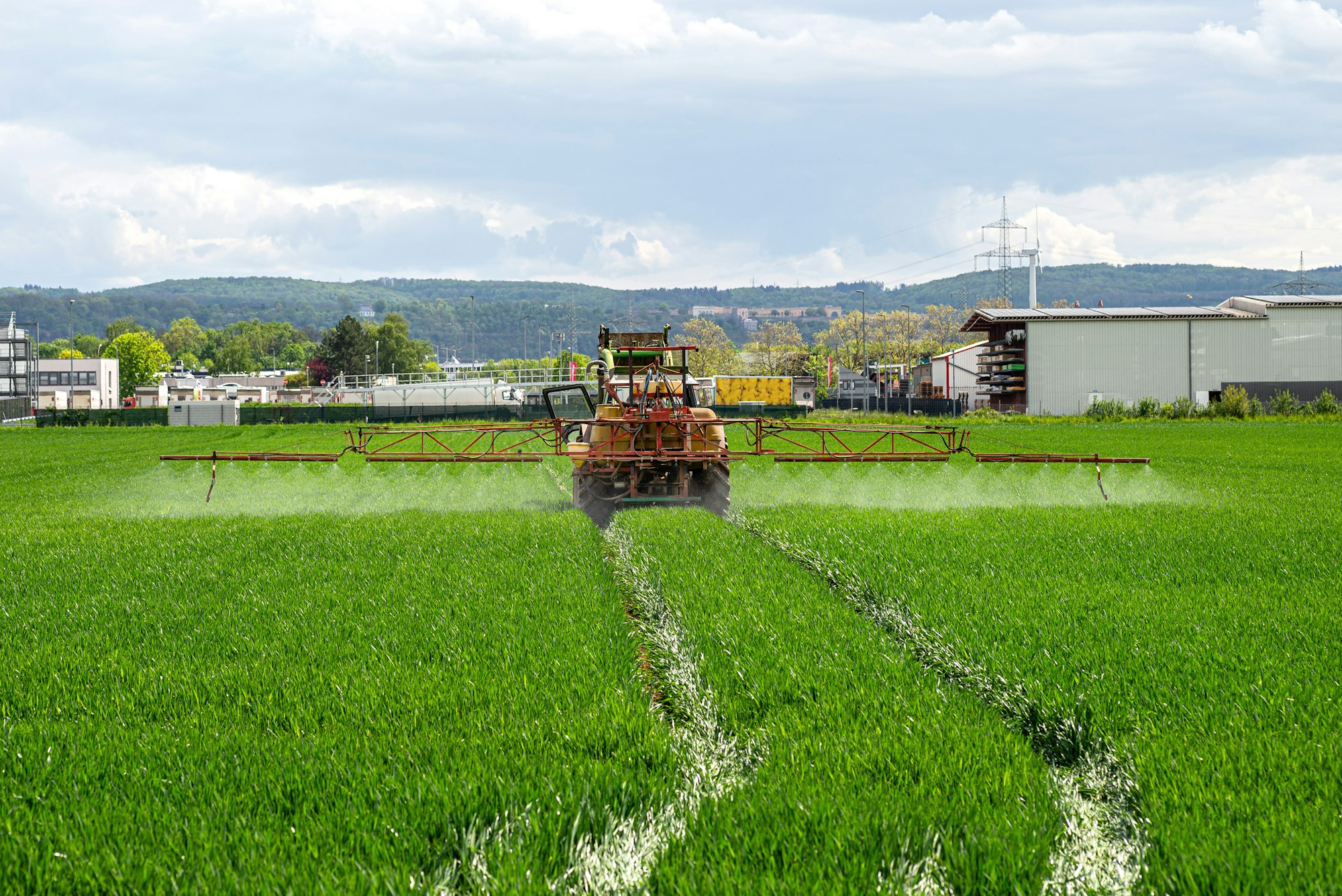 Spraying a crop field with a tractor that has a tank with spray nozzles.