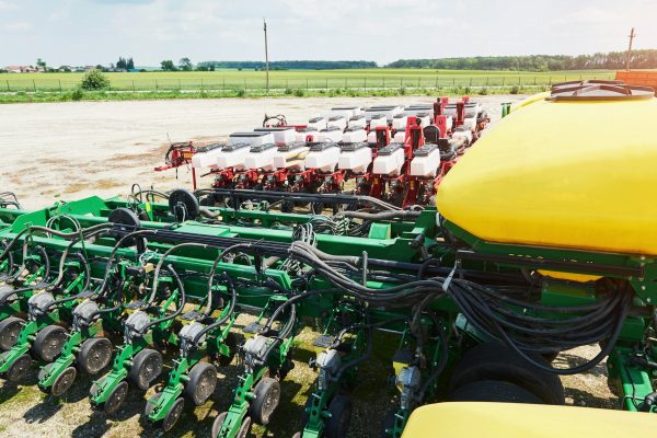Close up of seeder attached to tractor in field. Agricultural machinery for spring works sowing